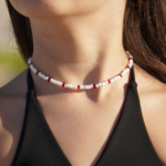 Closeup of Paradise Red seed bead necklace on model. White seed bead necklace with red accent beads.