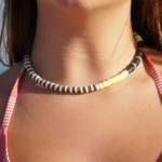 Purple, yellow, & black Bermuda Triangle heishi necklace closeup view on model's neck.