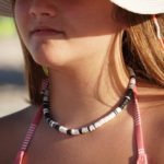 North Star black & white heishi necklace on model in pink & white swimsuit and hat