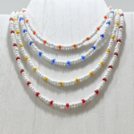 Paradise Orange displayed with multiple white seed bead choker necklace with red, orange, blue, and yellow accent beads