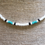 Close up view of seed bead necklace with white, seafoam, & black glass seed beads