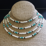 Multiple seed bead necklaces. Each necklace has white, seafoam, & black seed beads in a traditional surf style pattern.