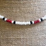 Detailed close up photo of Siren Necklace with white, red, & black glass seed beads in a traditional surf style pattern.