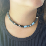 Storm Front sky blue, white, black, & gray heishi choker necklace close up on model in black shirt.