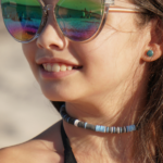 Storm Front sky blue, white, black, & gray heishi choker necklace on smiling model in sunglasses.