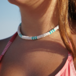 Detailed view of Surf's Up necklace designed with white & turquoise heishi beads in traditional surfer pattern on model's neck.