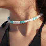 Detailed view of Surf's Up necklace designed with white & turquoise heishi beads in traditional surfer pattern on model's neck.