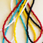 Sails collection of seed bead necklaces with all colors, red, white, yellow, seafoam, black, displayed together.