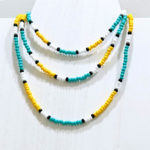 Multiple Tropical Sun, necklace made from yellow, seafoam, black, and white glass seed beads, displayed on white wooden jewelry bust.