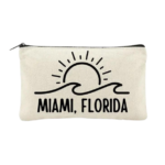 Miami Sun & Surf Canvas Zipper Pouch displayed on white background. Miami, Florida, wave outline, sun outline printed in black on light beige canvas pouch.