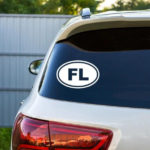 Florida Vinyl Decal white decal of FL in Oval displayed on back window of beige hatchback car with dark tinting.