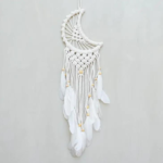 Moon Small Macrame Dreamcatcher displayed hanging against a light gray backdrop. Hoop on dreamcacher is white in color. Moon and tassels are white cotton macrame. Tassels are finished with white goose feathers.