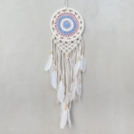 Pastel Small Macrame Dreamcatcher displayed hanging against a light gray backdrop. Hoop on dreamcacher is a white circle. Macrame pattern is a combination of pastel pinks and blues in nesting circles. Tassels are finished with white goose feathers.