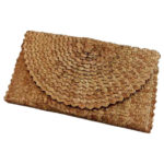 Woven Straw Clutch Brown pictured closed on a white background. Purse is made with brown palm fronds, is a rectangle, and displayed while closed.
