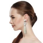 Beaded Post Statement Earrings Off White Pearl shown on profile of model with brown hair in ponytail. Post earring is made with off white seed and bugle beads and is in a knot pattern with beaded fringe hanging down below the knot.